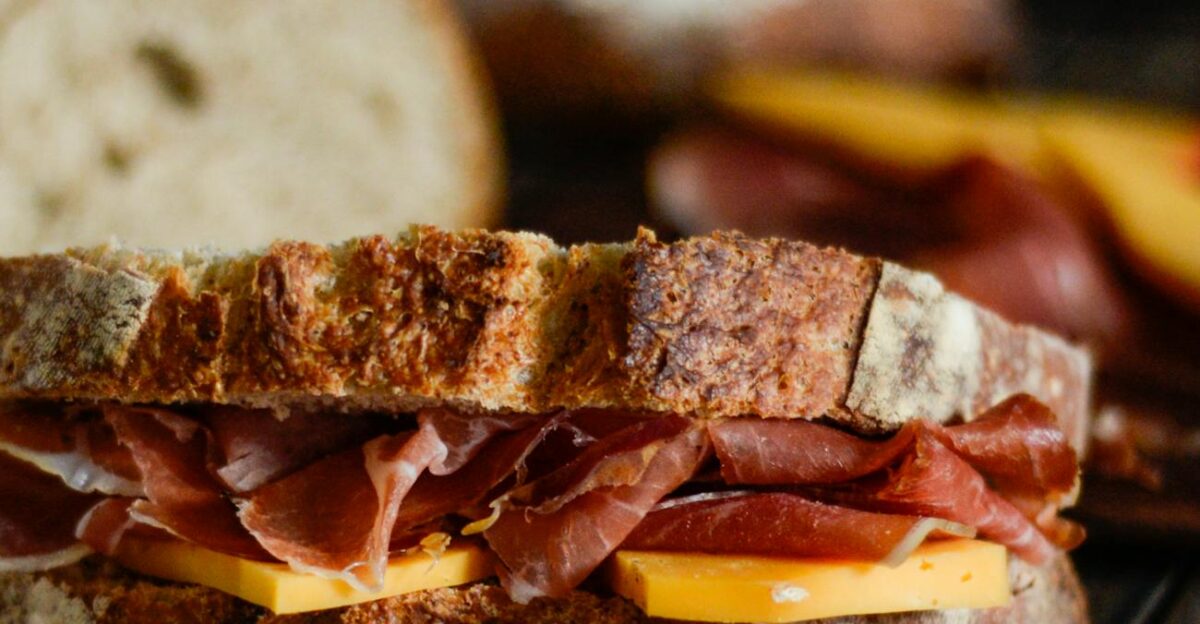 Close-up of a rustic sandwich with ham and cheese on a wooden table