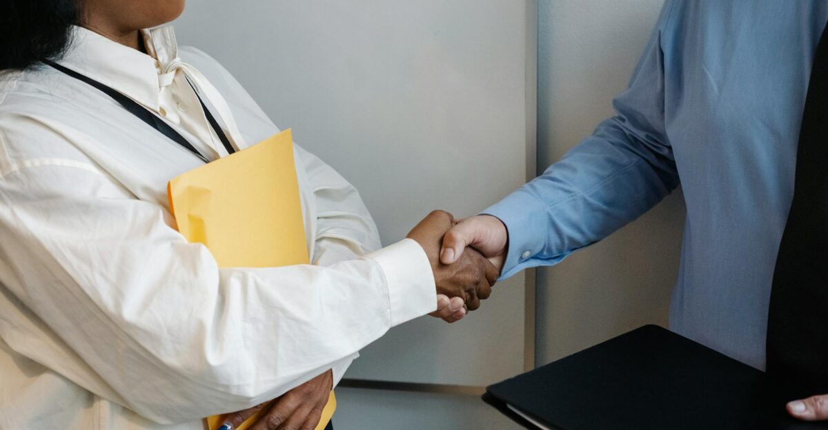 Two professionals shaking hands in an office setting symbolizing agreement
