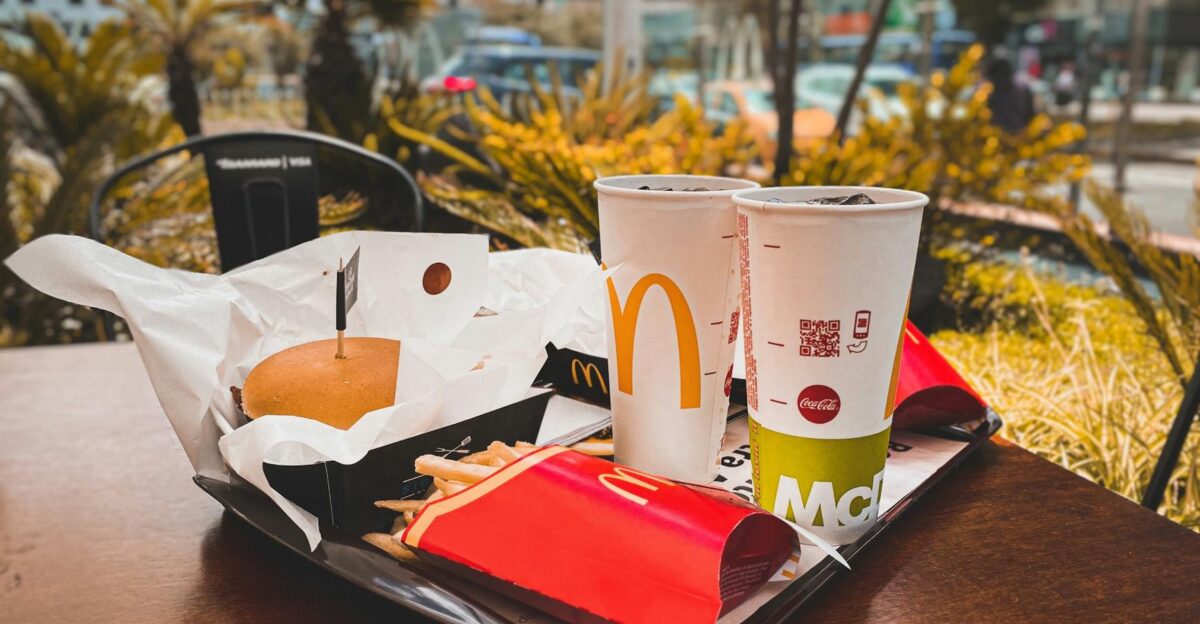 An appetizing fast food meal with burger french fries and drinks on an outdoor table in urban setting