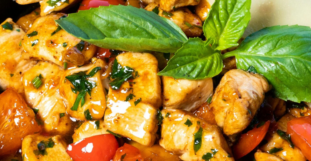 A vibrant grilled chicken salad garnished with fresh basil leaves and served in a rustic bowl.
