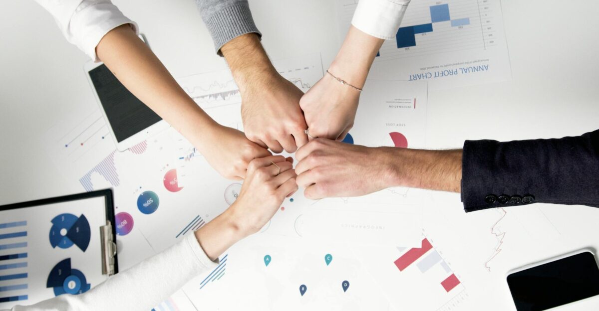 Colleagues celebrate success with a fist bump over financial charts depicting teamwork and unity