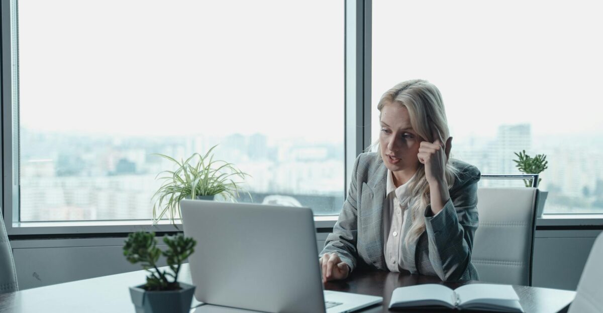 Professional woman engaged in a video meeting at a modern office desk with a laptop