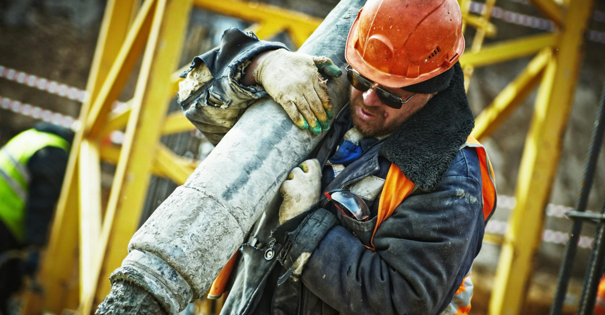 Construction worker in safety gear handling equipment on an active site.