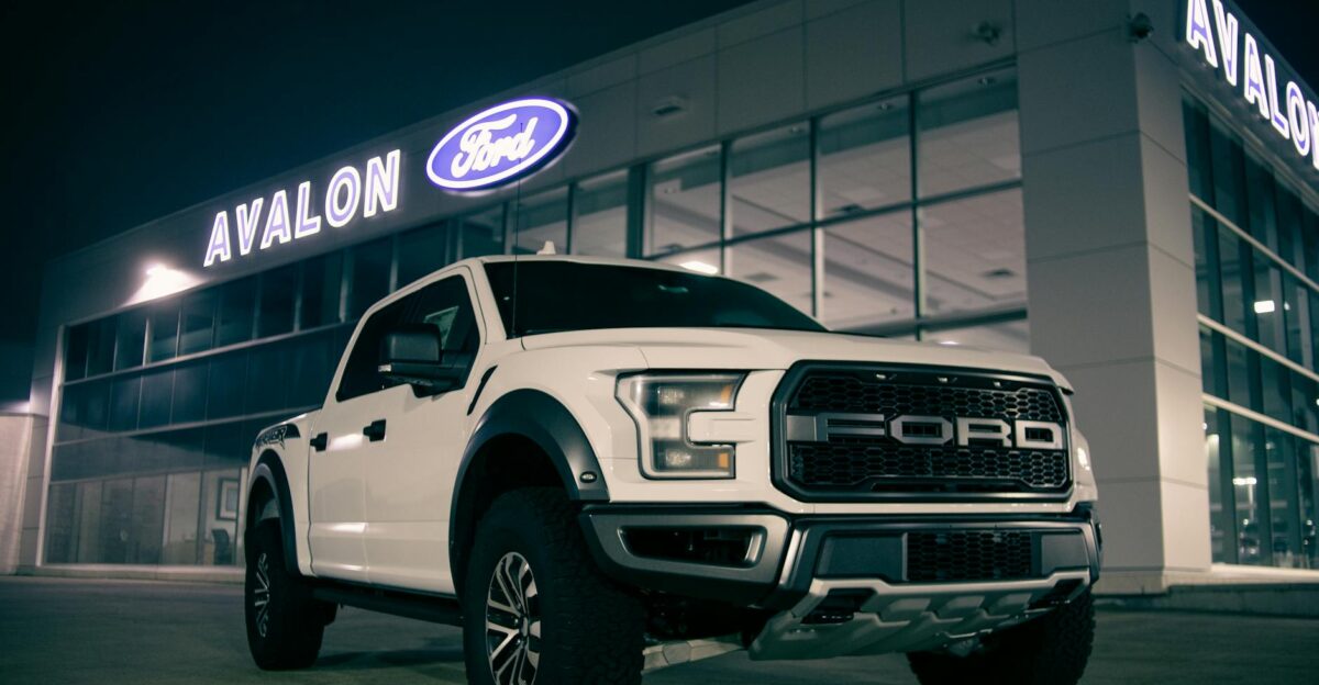 Low angle of modern pickup car with label on bumper on parking lot near retailing salon