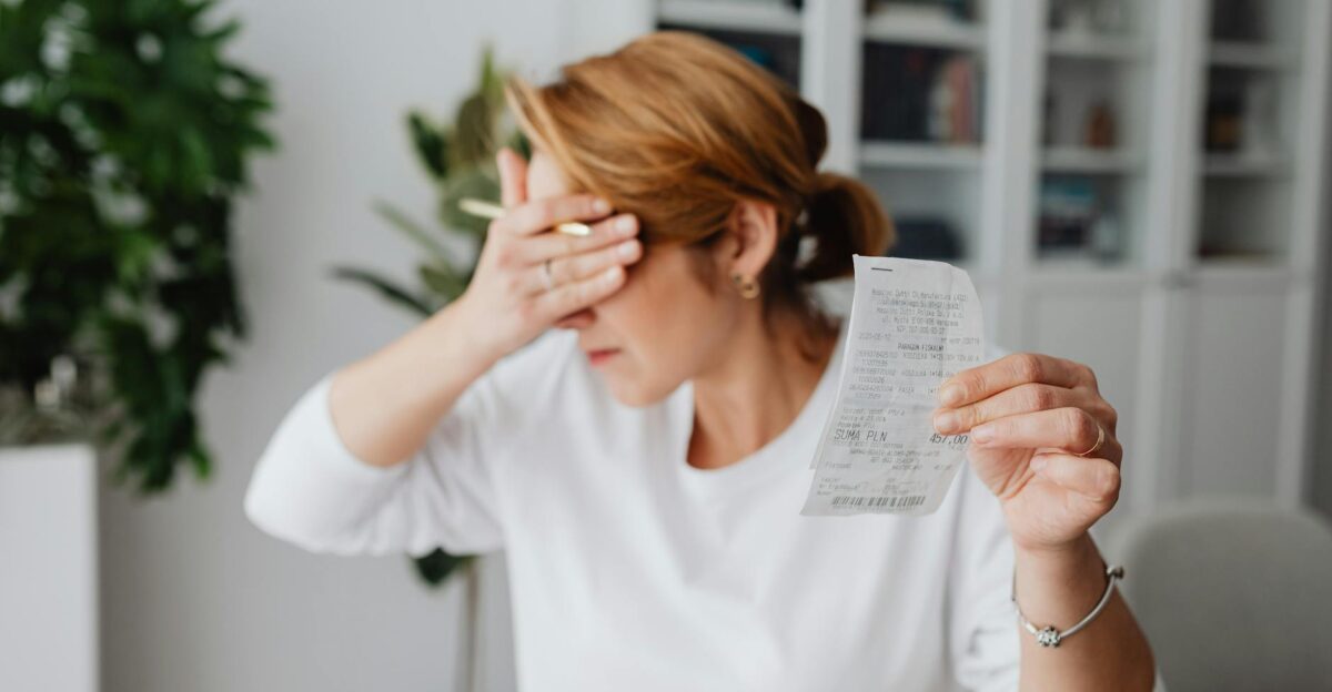 Woman experiencing stress while reviewing household expenses at home