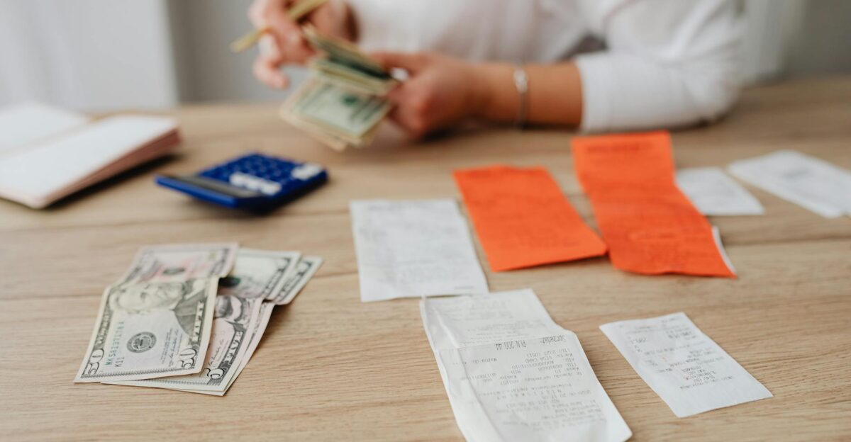 A person using a calculator and cash to plan a household budget