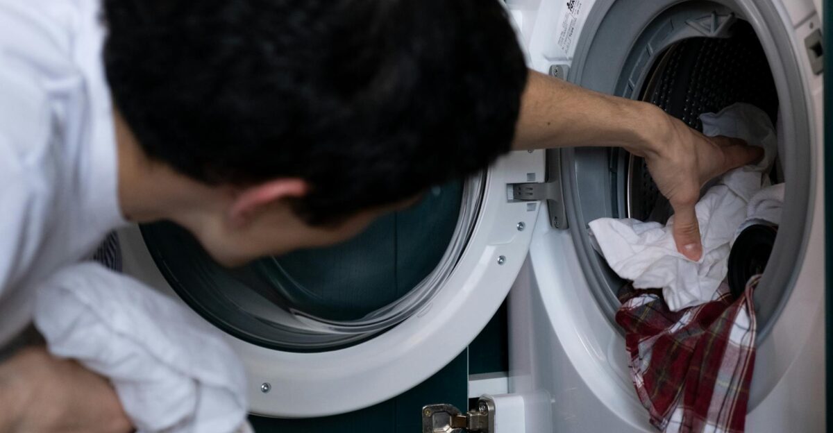 Close-up of a man placing clothes into a washing machine during household chores