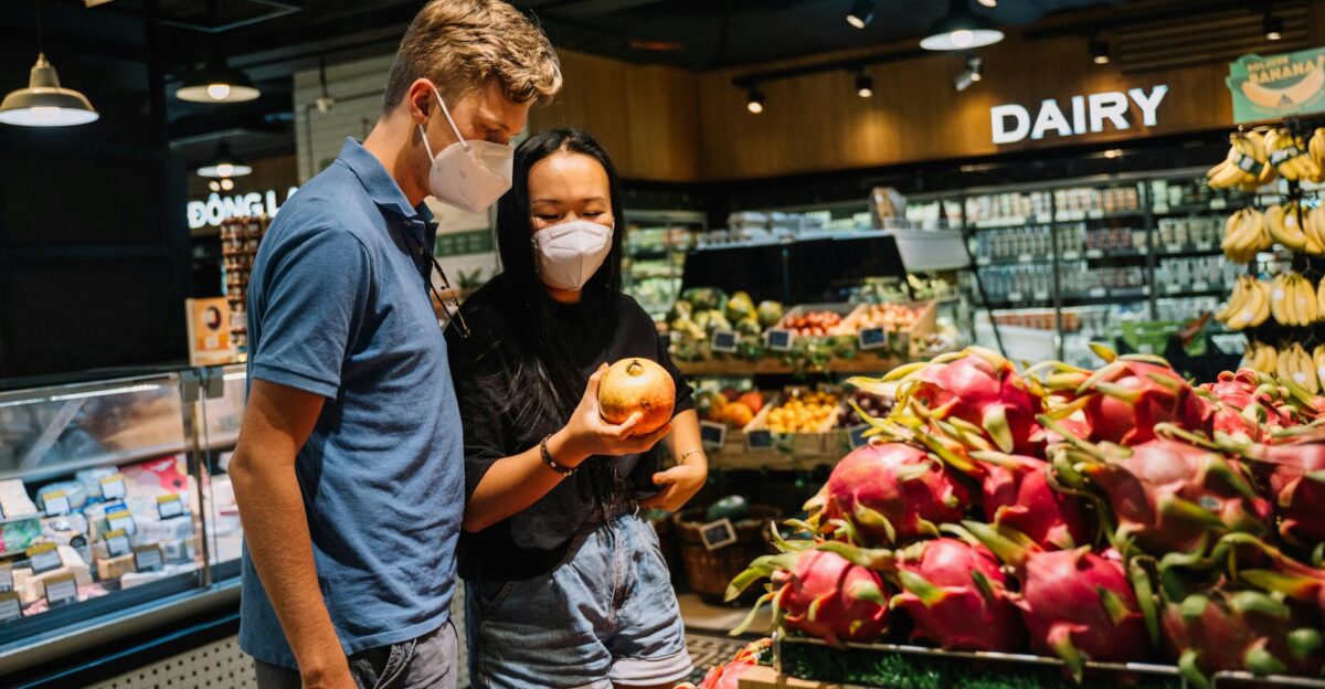 A couple wearing face masks shopping for fresh fruits at an indoor supermarket