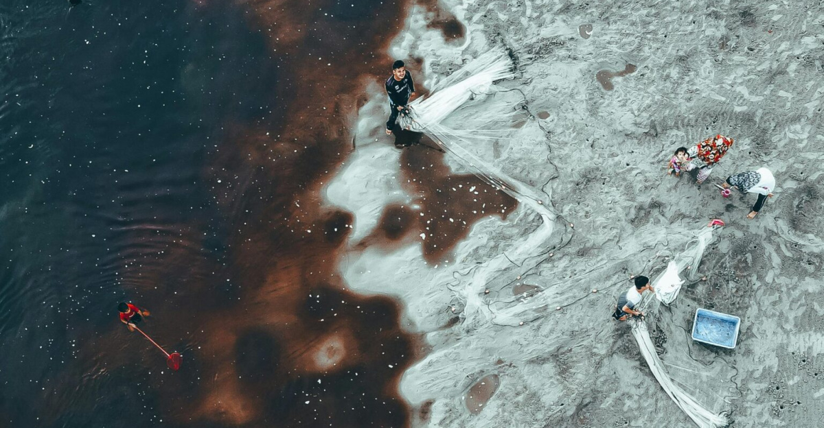 Aerial photo of fishermen working in polluted waters, depicting environmental challenges.