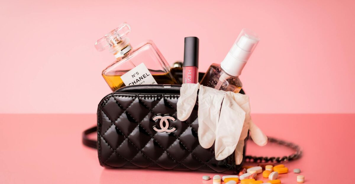 Chanel bag featuring perfume gloves and medicines on a pink surface for a mix of luxury and health