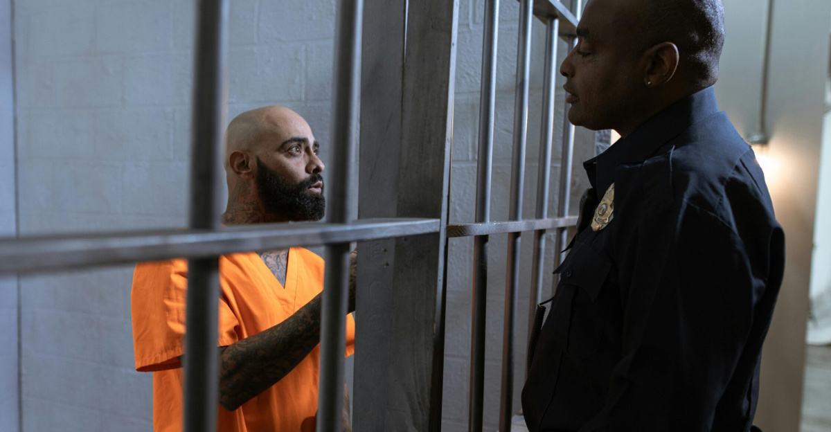 A guard converses with an inmate inside a prison cell, highlighting the justice system setting.