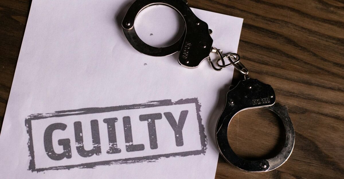 Top view of handcuffs on paper with GUILTY text symbolizing a verdict or crime