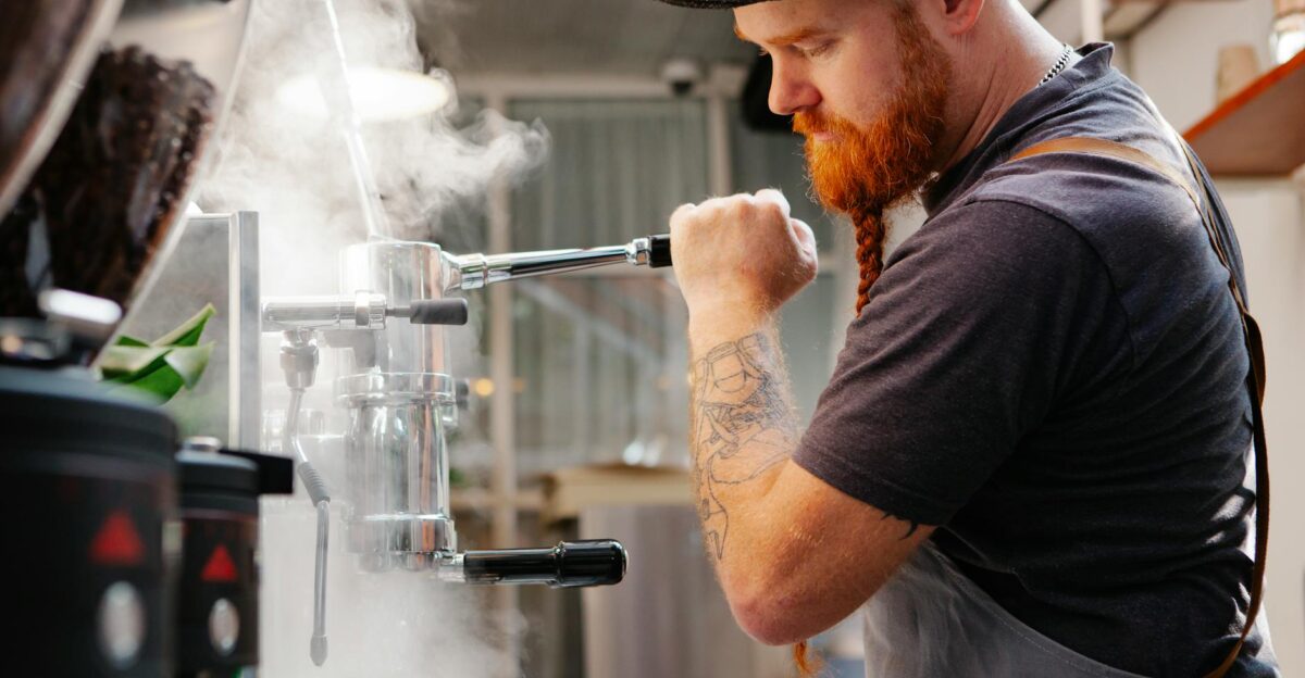 Focused barista using an espresso machine creating steam in a modern caf setting