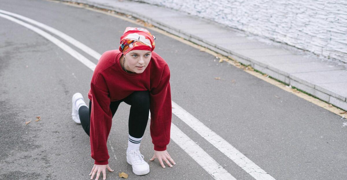Woman in athletic wear getting ready for a sprint start on a city road