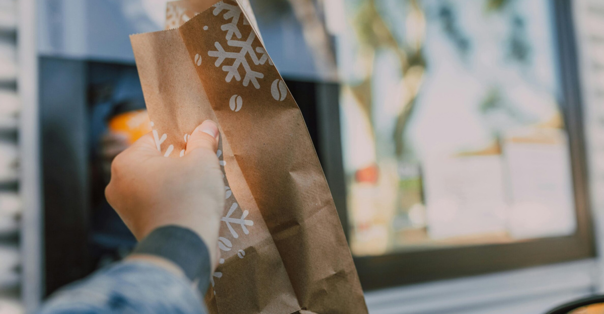 Hand reaching out with brown paper bag at drive-thru window, showcasing casual takeout.