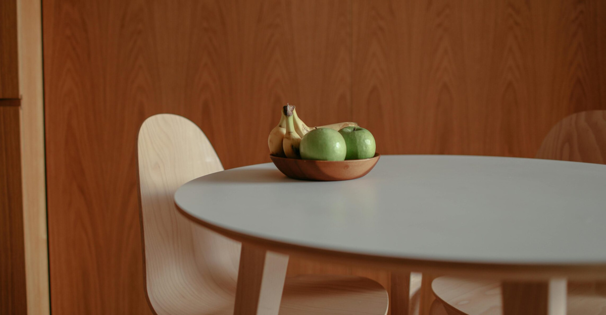 A simple fruit bowl with green apples and bananas on a sleek wooden table, perfect for a modern kitchen.