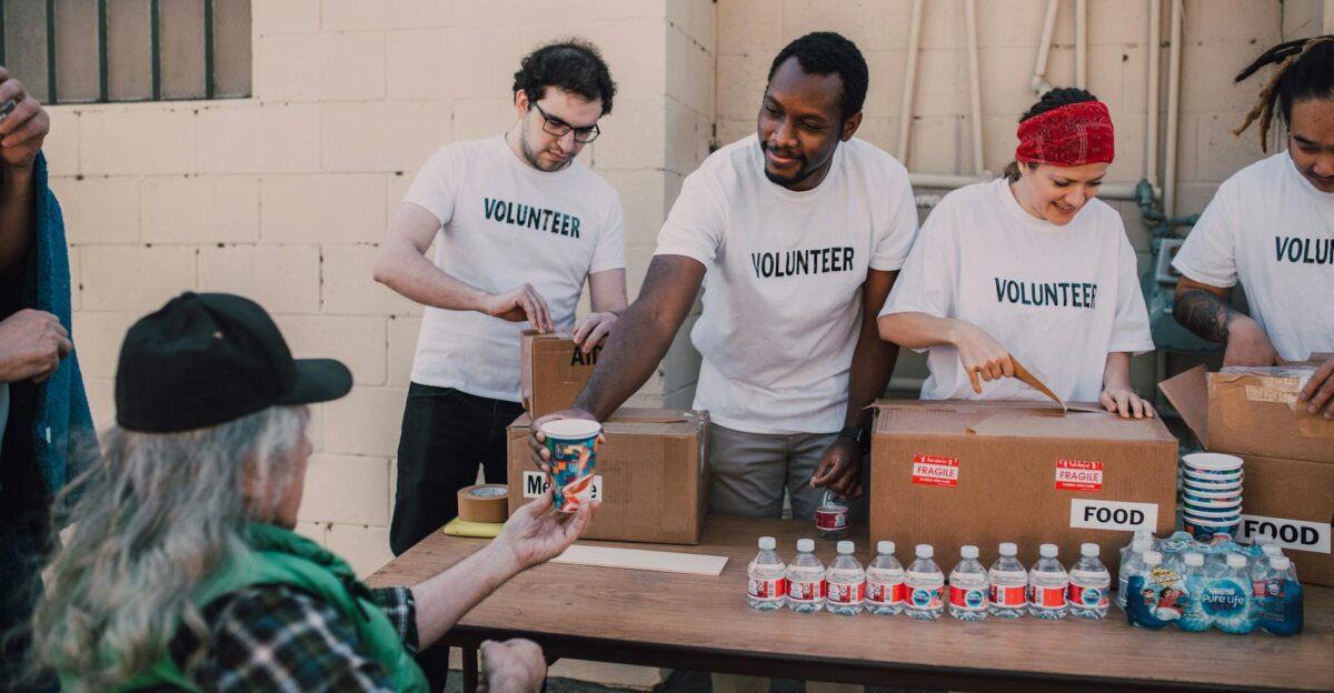 Volunteers distribute food and drinks to the needy at an outdoor charity event