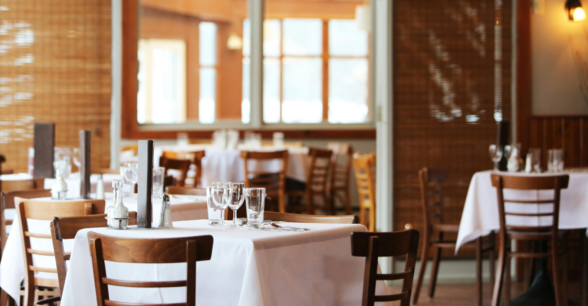 A serene restaurant interior with wooden chairs and tables set with glasses, ready for dining.