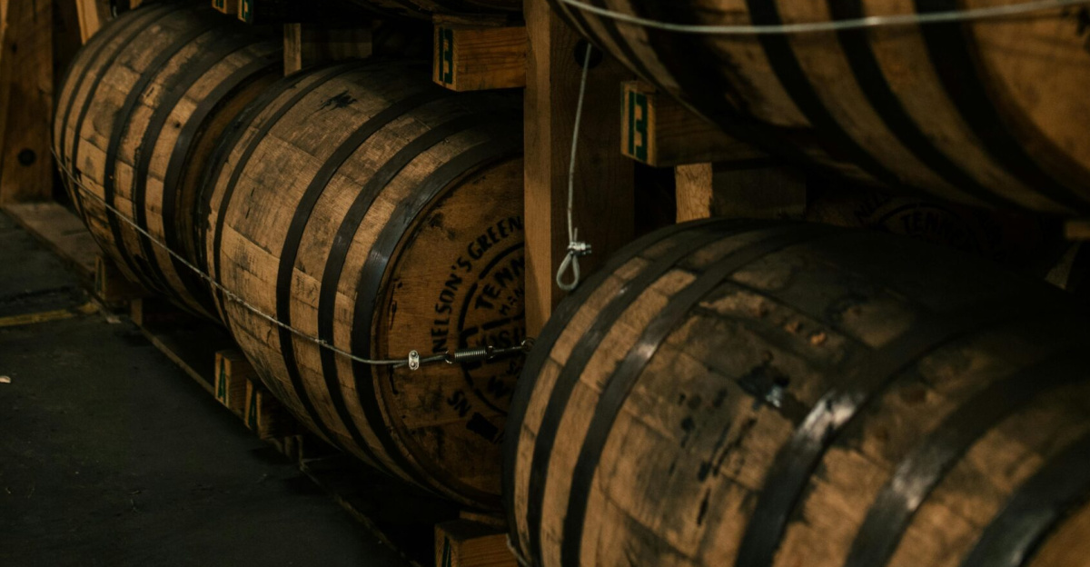 A vertical shot of wooden barrels neatly stacked in a distillery's storage room.