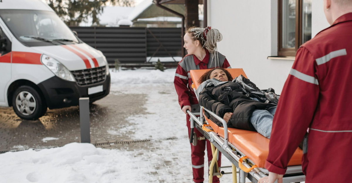 Emergency responders transport a patient on a stretcher outside in snowy conditions.