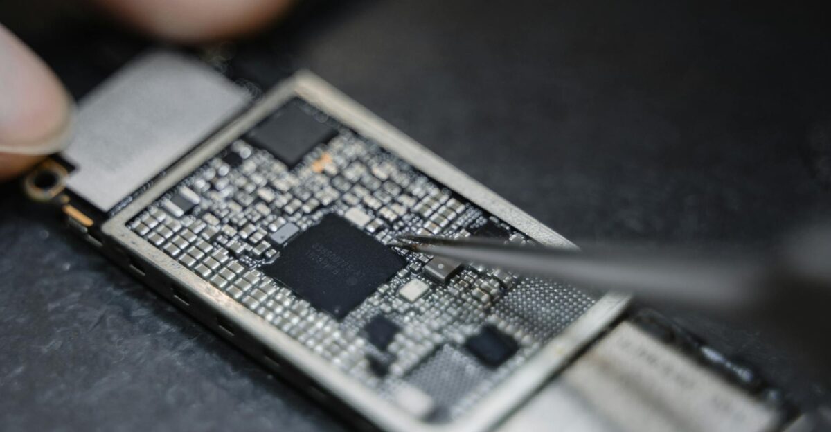Detailed view of a technician using tweezers to fix an electronic circuit board