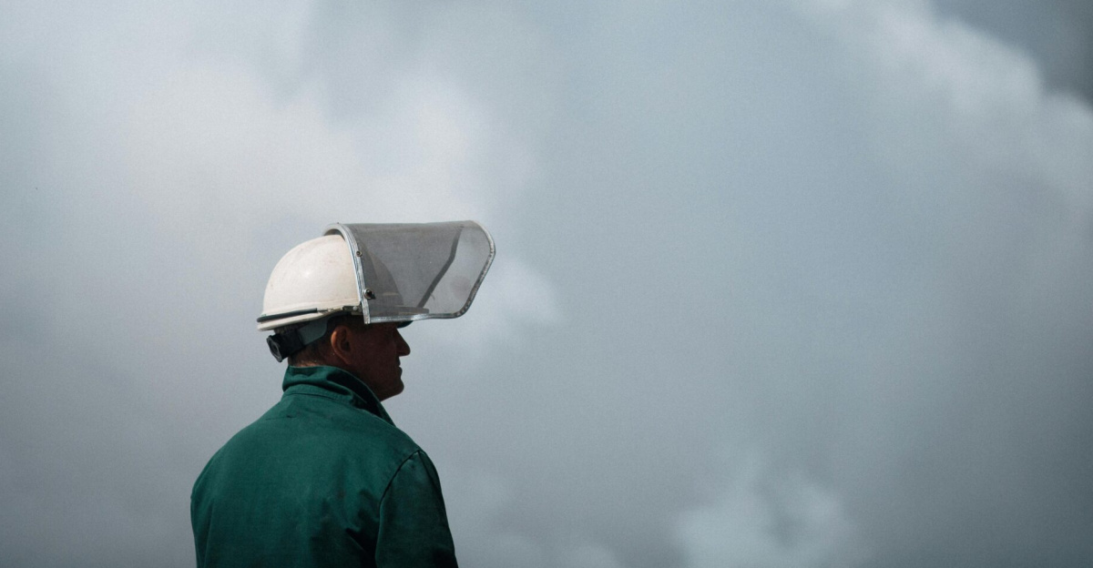 A worker in protective gear stands in front of thick smoke, highlighting industrial air pollution.