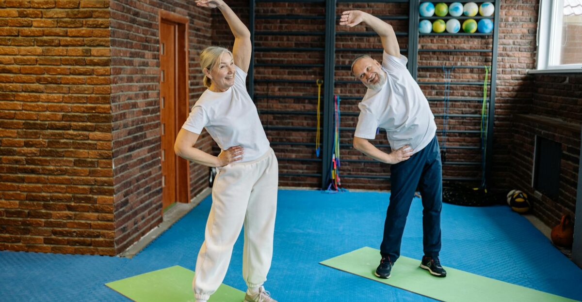 Elderly couple stretching on yoga mats in a home gym embracing a healthy lifestyle