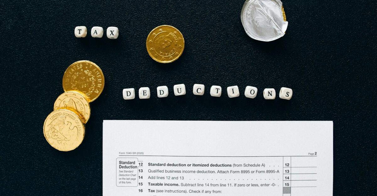 Image of tax deductions concept with coins and tax form on black background