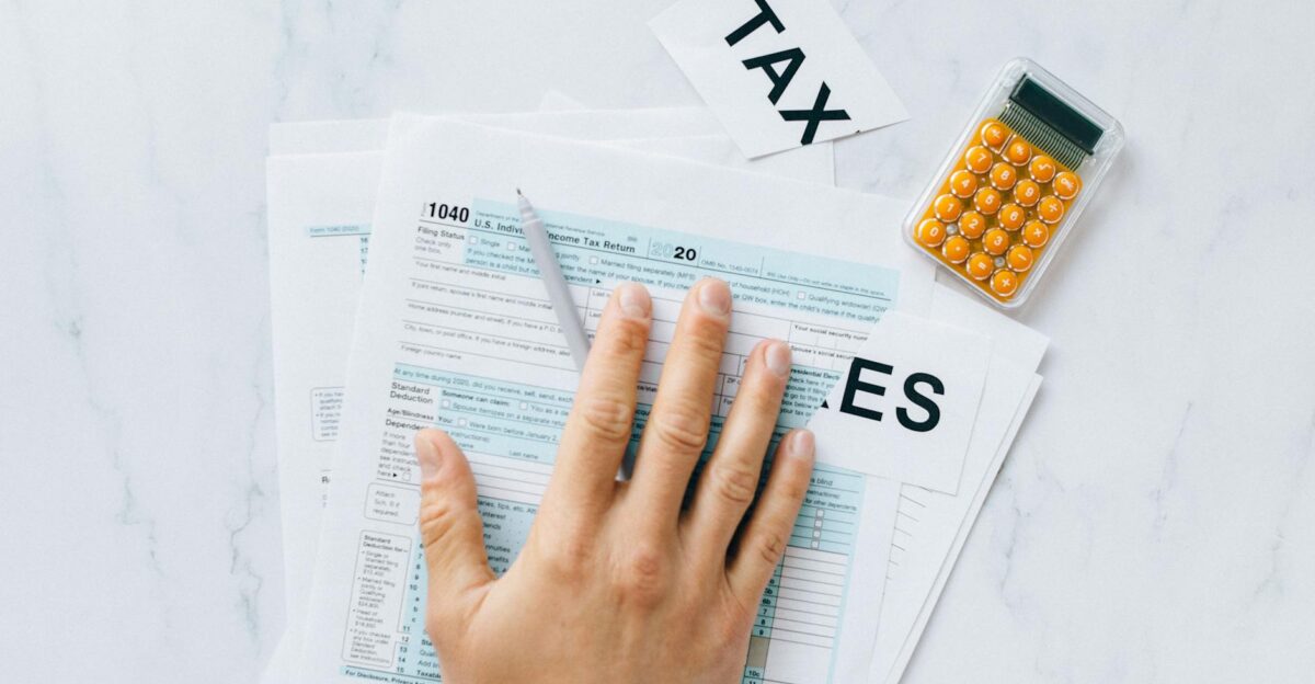 Close-up of a hand on tax form 1040 with a calculator on a desk