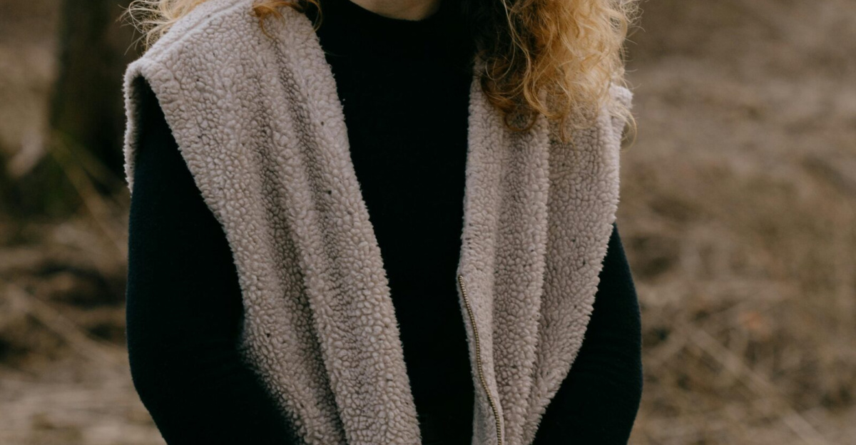 Portrait of a woman with curly hair posing in a field in Durbuy, Belgium.
