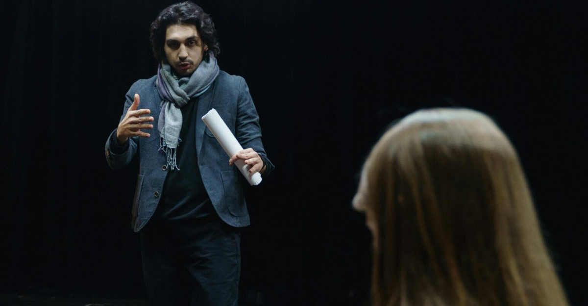 Actors and director engage in a focused rehearsal inside a theater, studying scripts intensely.