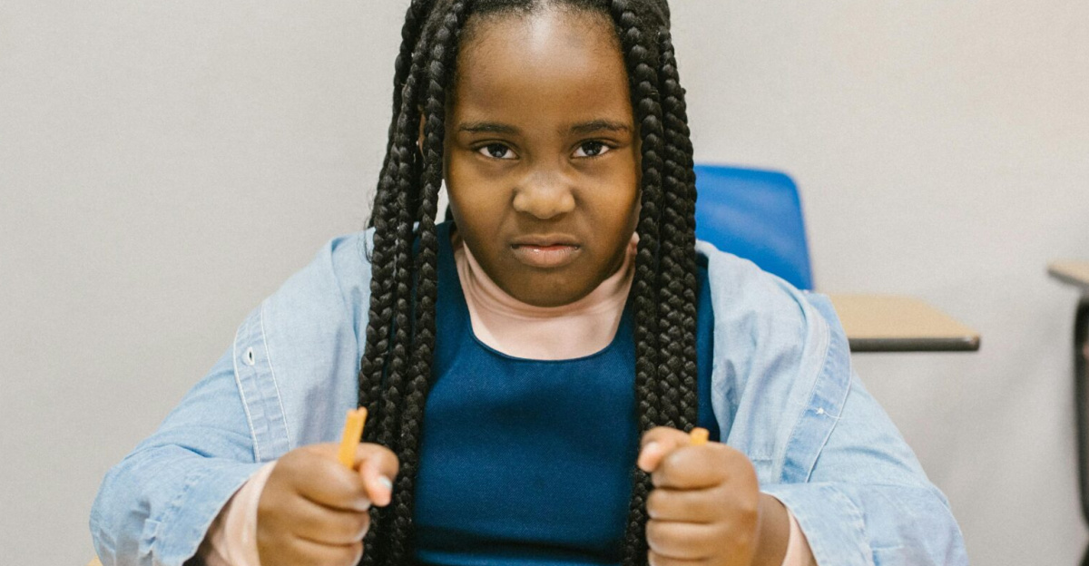 A young girl sits at a desk with a determined expression, promoting anti-bullying.