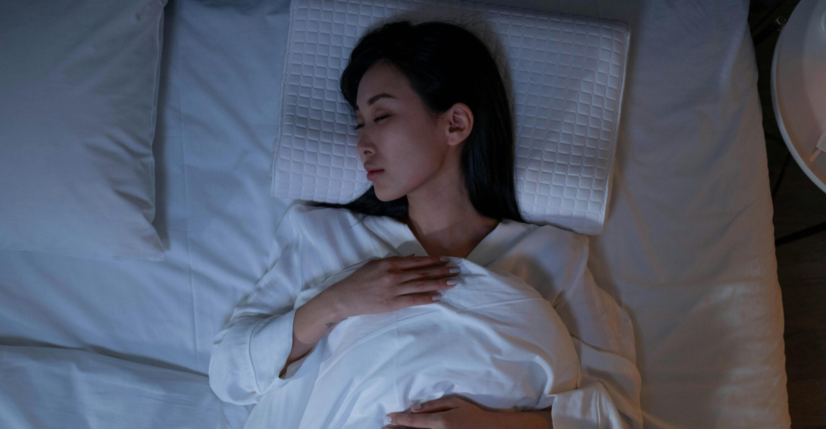 Calm and peaceful woman resting in bed under dim lighting, promoting relaxation.
