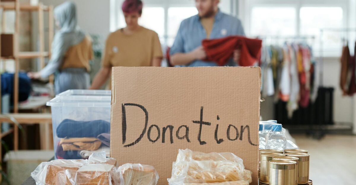 Volunteers sort clothes and food in a donation center Cardboard sign reads Donation