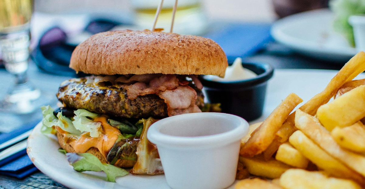 Close-up of a juicy burger and crispy fries served with sauces perfect for a hearty meal