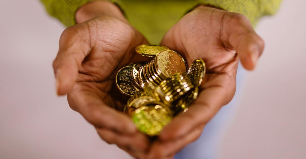 Close-up of hands cupping shiny gold coins symbolizing wealth and prosperity
