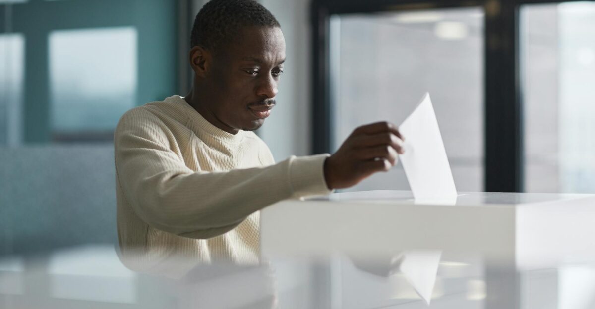 A young man casting his vote at an indoor polling station focused on the democratic process
