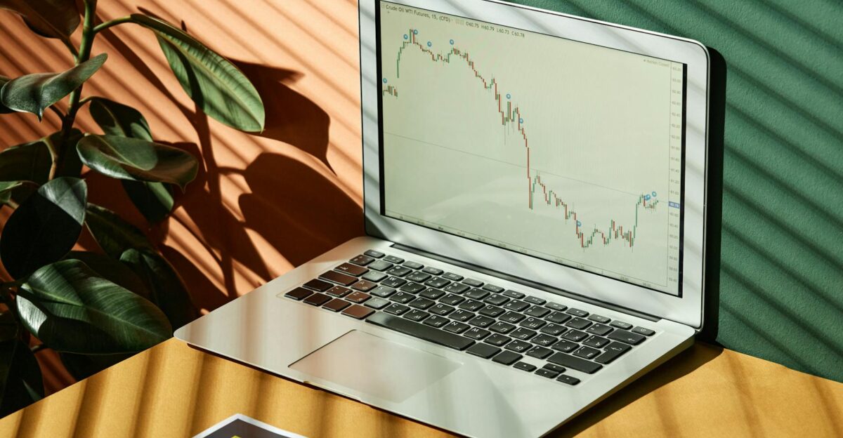 Laptop displaying a financial graph with reports in a sunlit workspace
