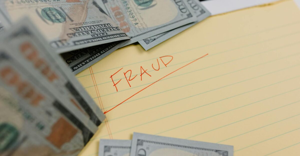 Close-up of US dollars and Fraud written on yellow paper representing financial scams