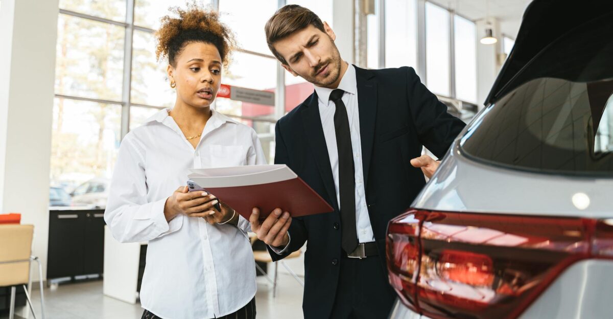 A professional consultation at a car dealership involving a sales agent and a customer discussing a vehicle purchase