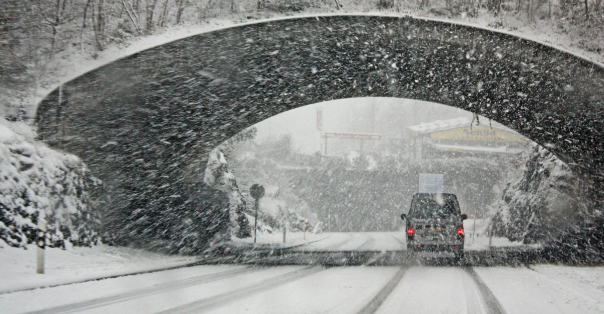 A winter storm covers a Swiss bridge in snow, creating a beautiful yet hazardous landscape.