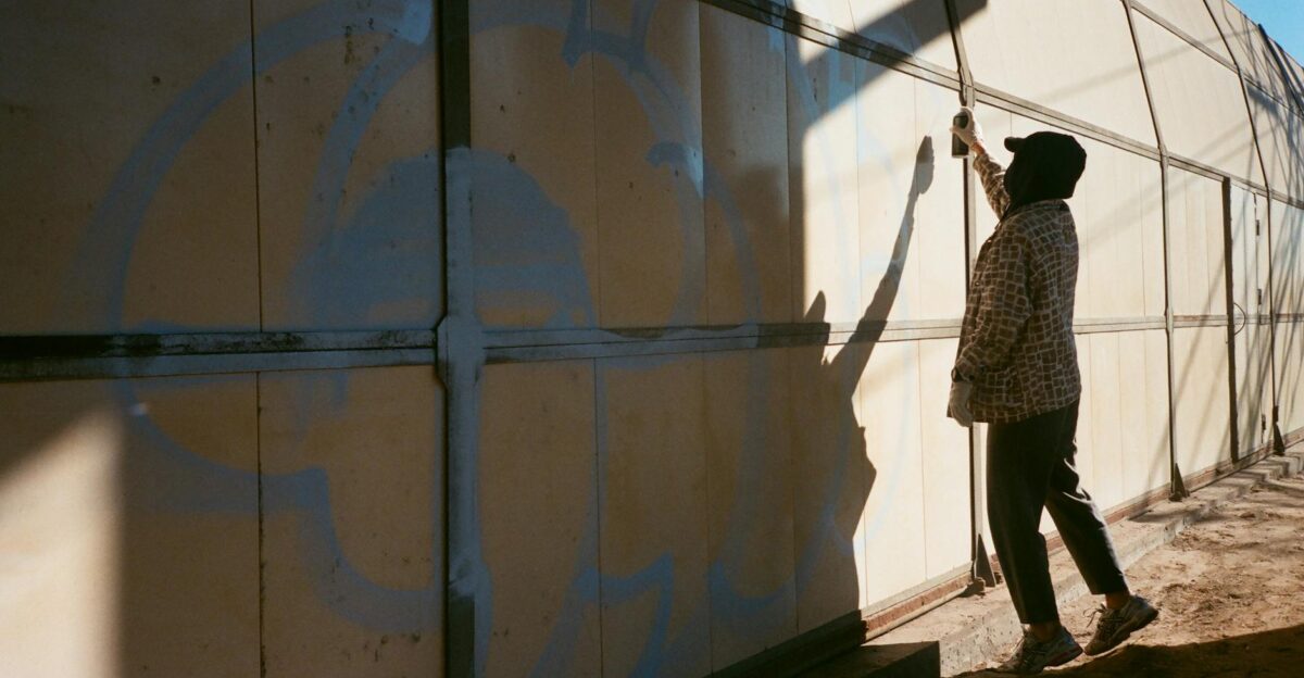 Silhouette of an artist spray painting graffiti on an urban wall