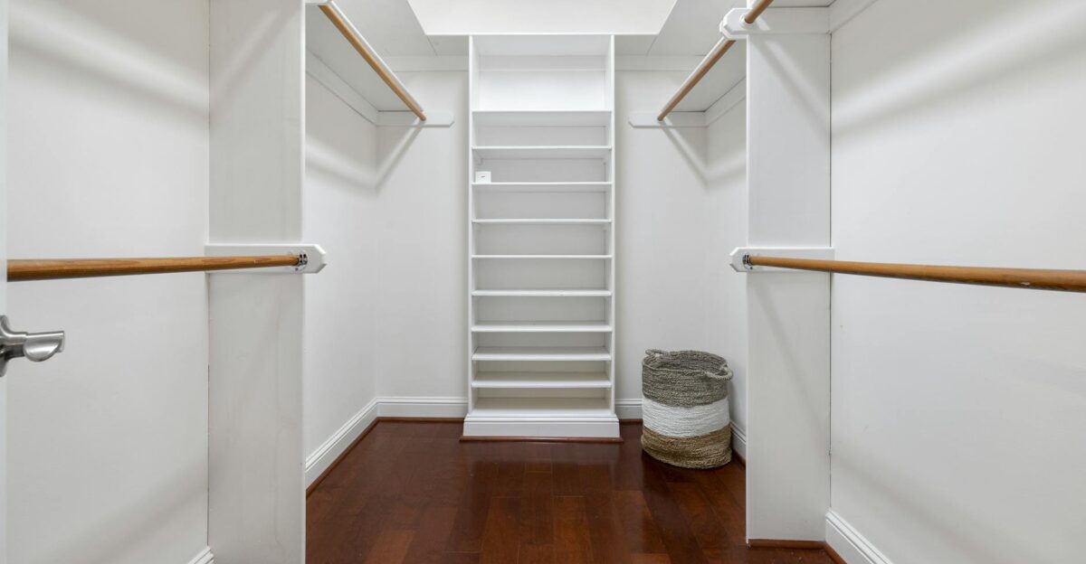 Minimalist empty walk-in closet featuring wooden floors shelves and hanging rods