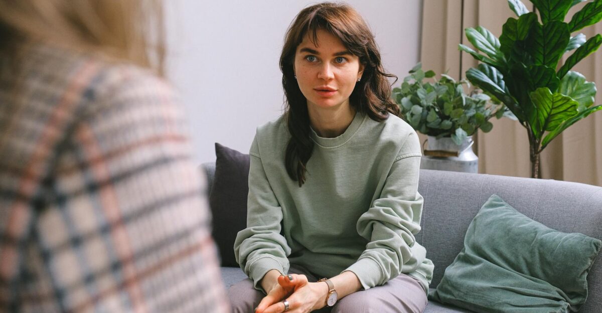A focused woman during a therapy session seated on a sofa indoors