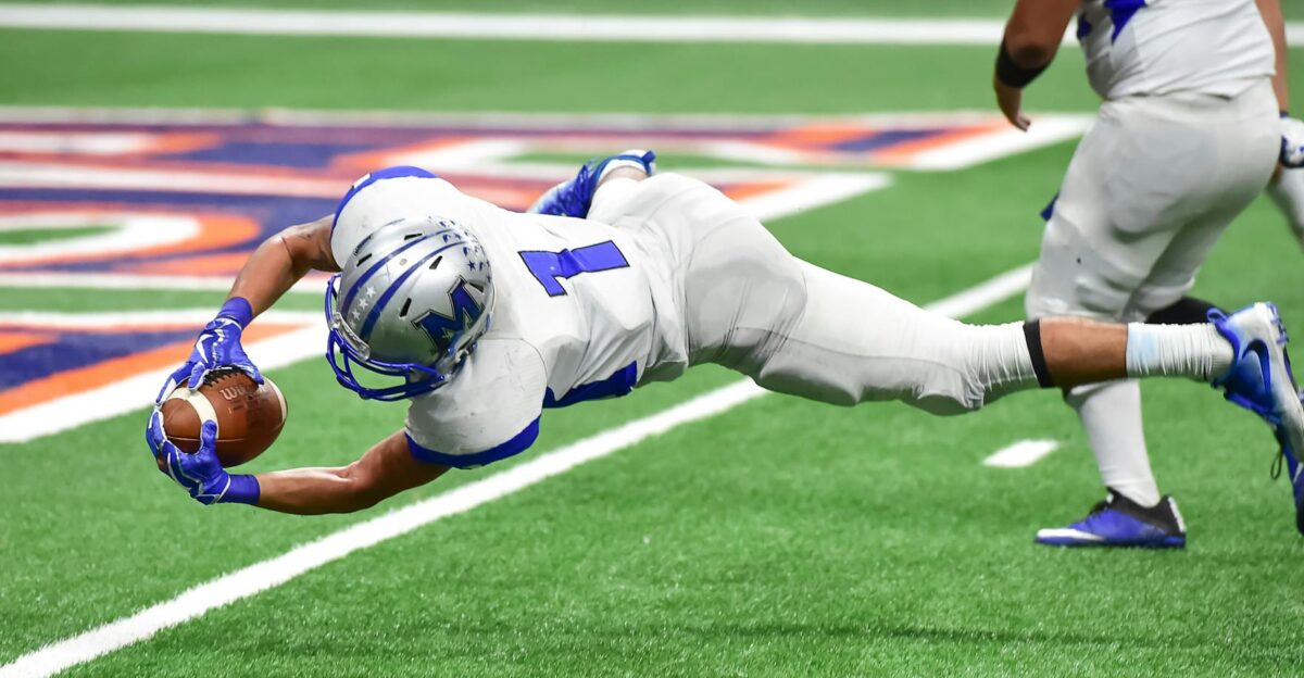Football player making an incredible diving catch during a high-energy game in the stadium