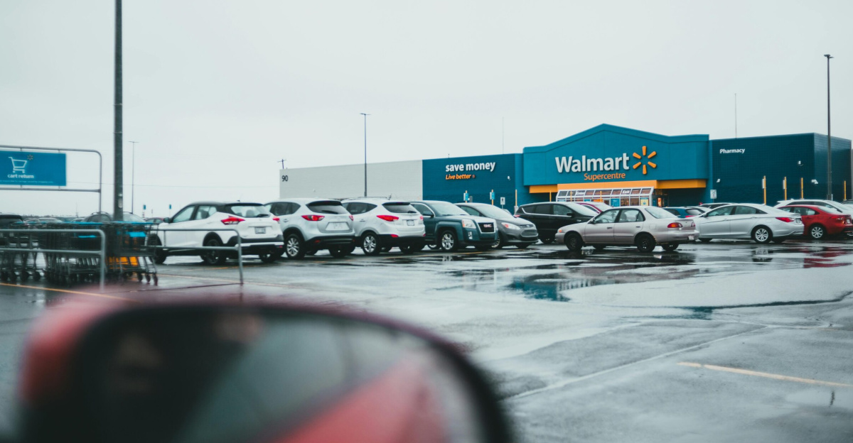 Red car with mirror parked near store in parking lot on street on autumn day