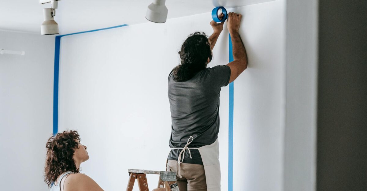 A man and woman working together on home renovation applying painter s tape