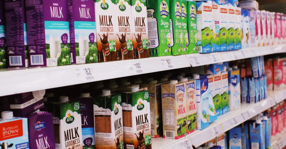 Various milk cartons displayed on shelves in a bright supermarket aisle.