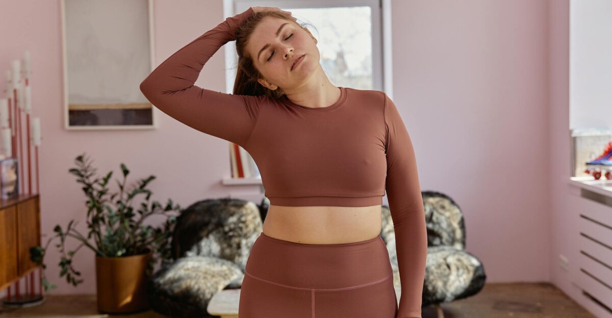 Relaxed plus-size woman in activewear stretching at home focusing on fitness and wellness