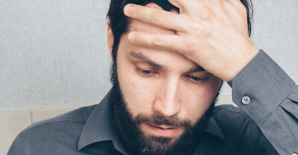 A stressed man looks at his smartphone holding a credit card in his hand